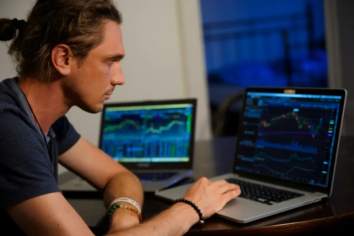 Analyst Monitoring Stock Charts on Dual Laptops